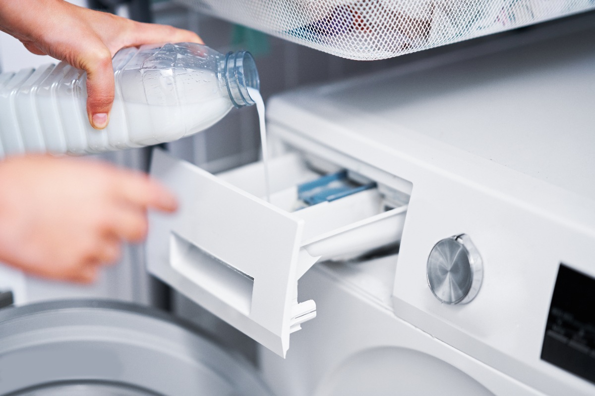 Main versant du liquide dans le tiroir à lessive du lave-linge