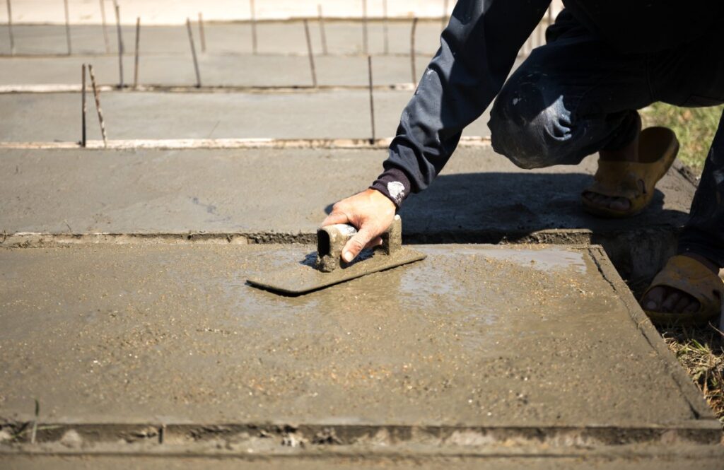 Un ouvrier de bâtiment lissant une surface en dalle béton
