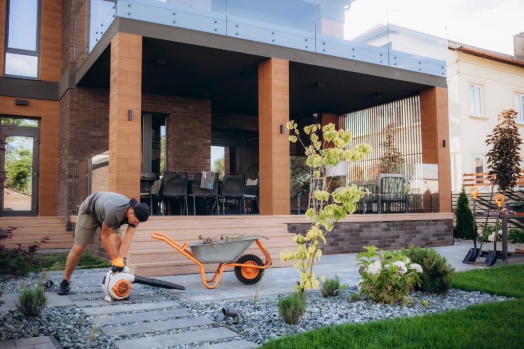 Un homme qui utilise une souffleur de feuilles dans la cour