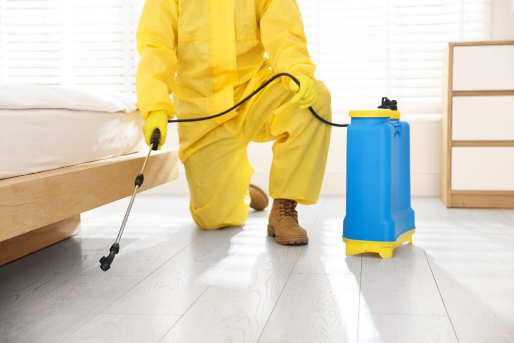 Une personne en combinaison de protection qui vaporise une chambre