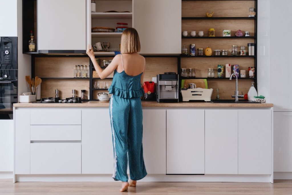 Une femme qui attrape une tasse dans le placard de cuisine