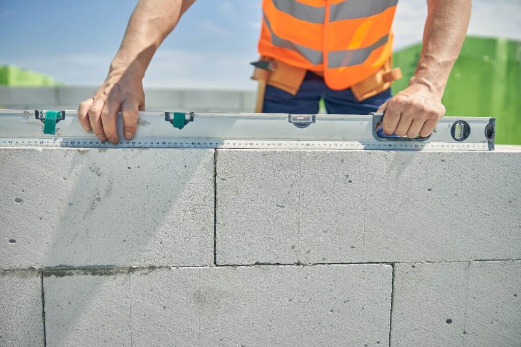 Un homme utilisant un niveau sur un mur en parpaings